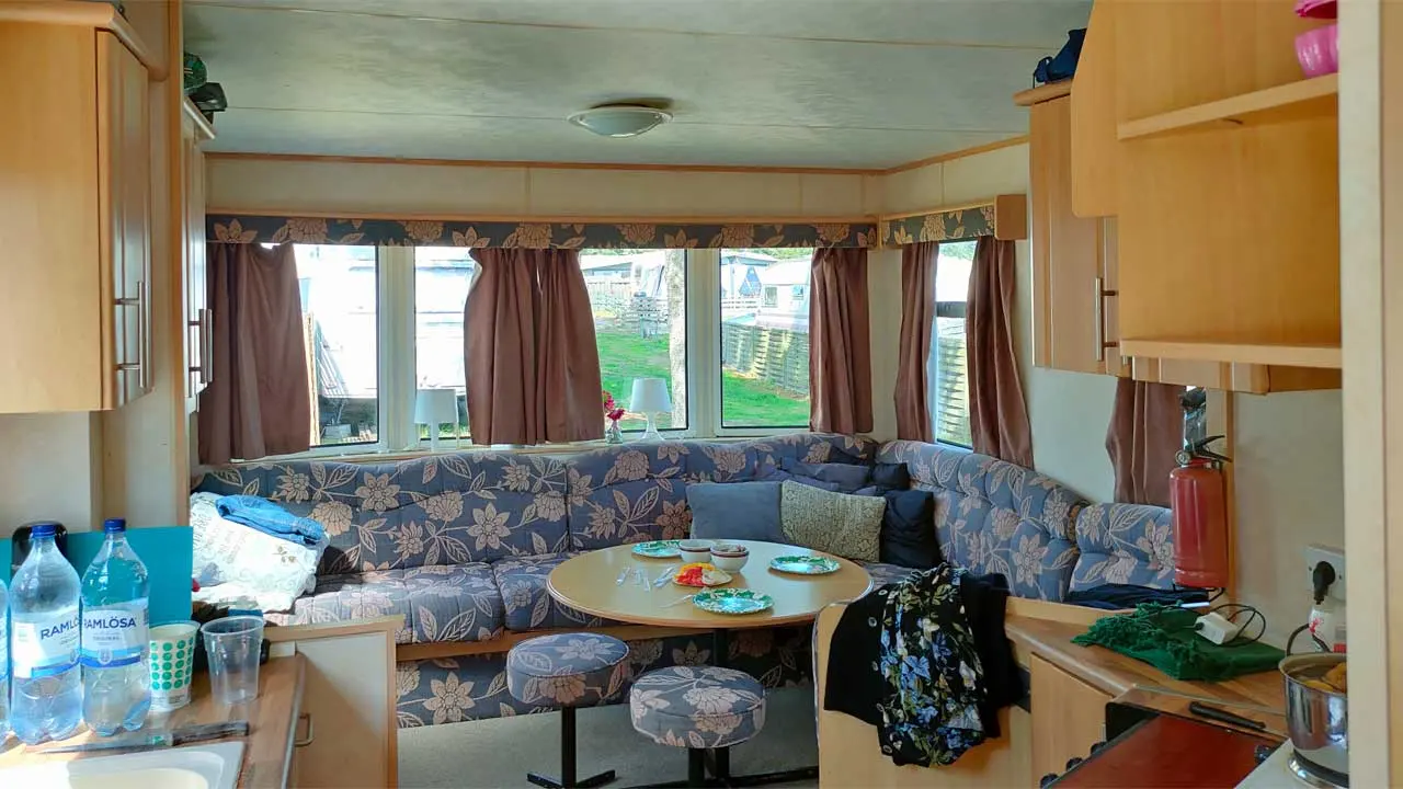 Inifrån en villavagn med soffa och bord vid fönstren